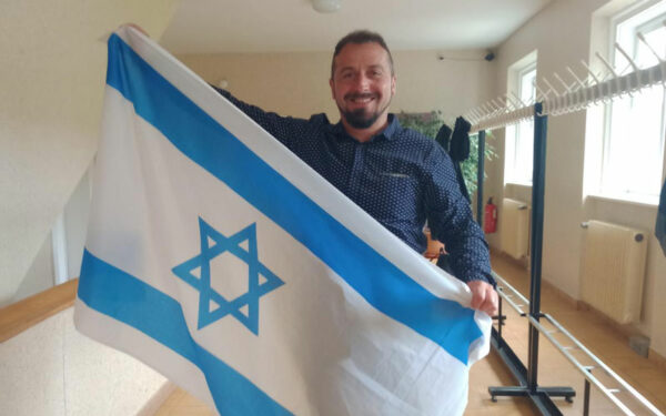 Ein Mann mit einer israelischen Flagge. Die Flagge hat einen blauen Davidstern.